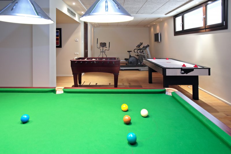 Basement home gym that has workout equipment and a pool table (Photo by Freefly - stock.adobe.com)